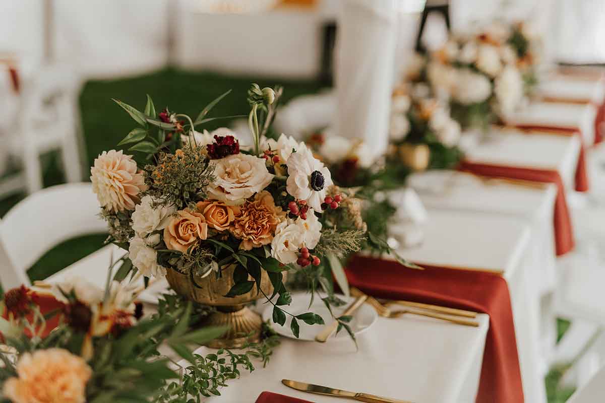 beautiful floral arrangement in fall hued colors on table with platting set up