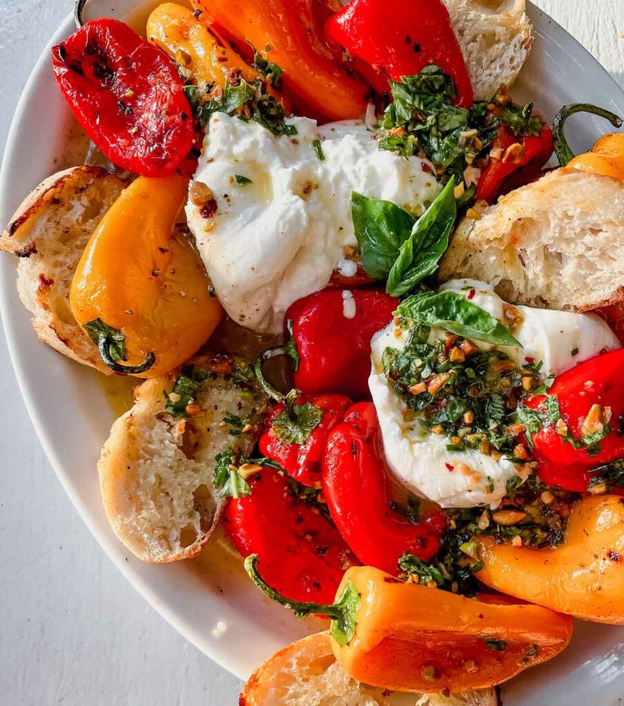 red, yellow mini peppers with burrata and bread on white plate
