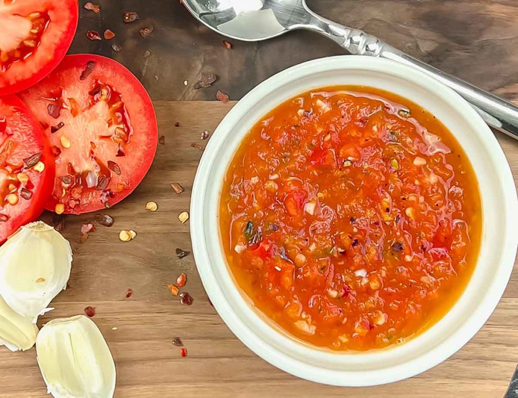 roma tomato sauce pureed with herbs on wood board in white ramekin