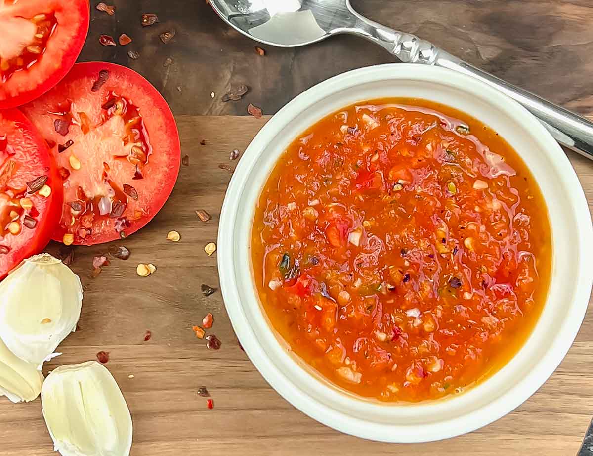 roma tomato sauce pureed with herbs on wood board in white ramekin