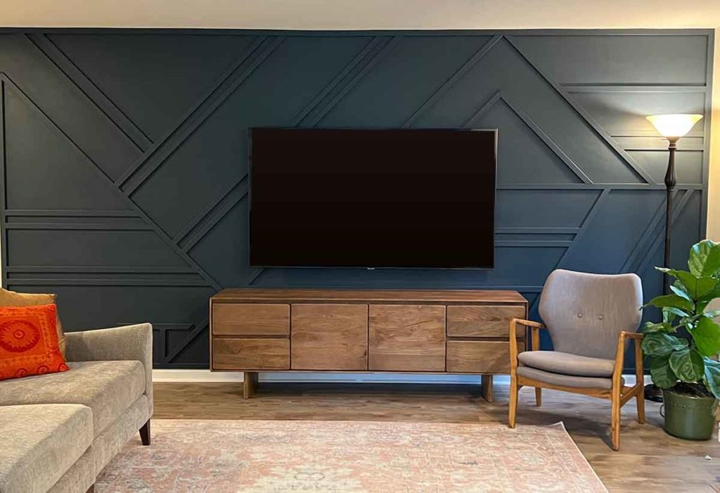 navy blue accent geometric accent wall with TV mounted above wood console