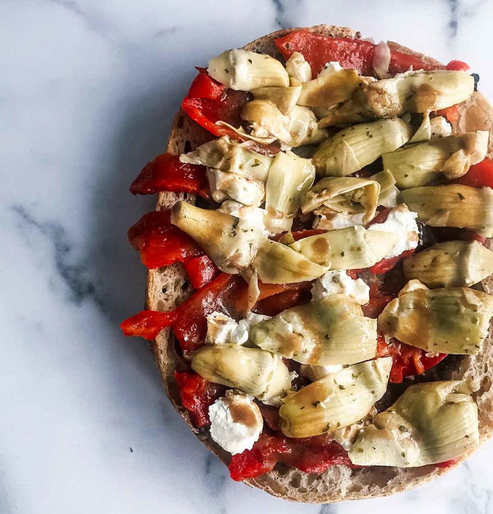 sandwich topped with cheese, roasted red peppers and artichokes hearts