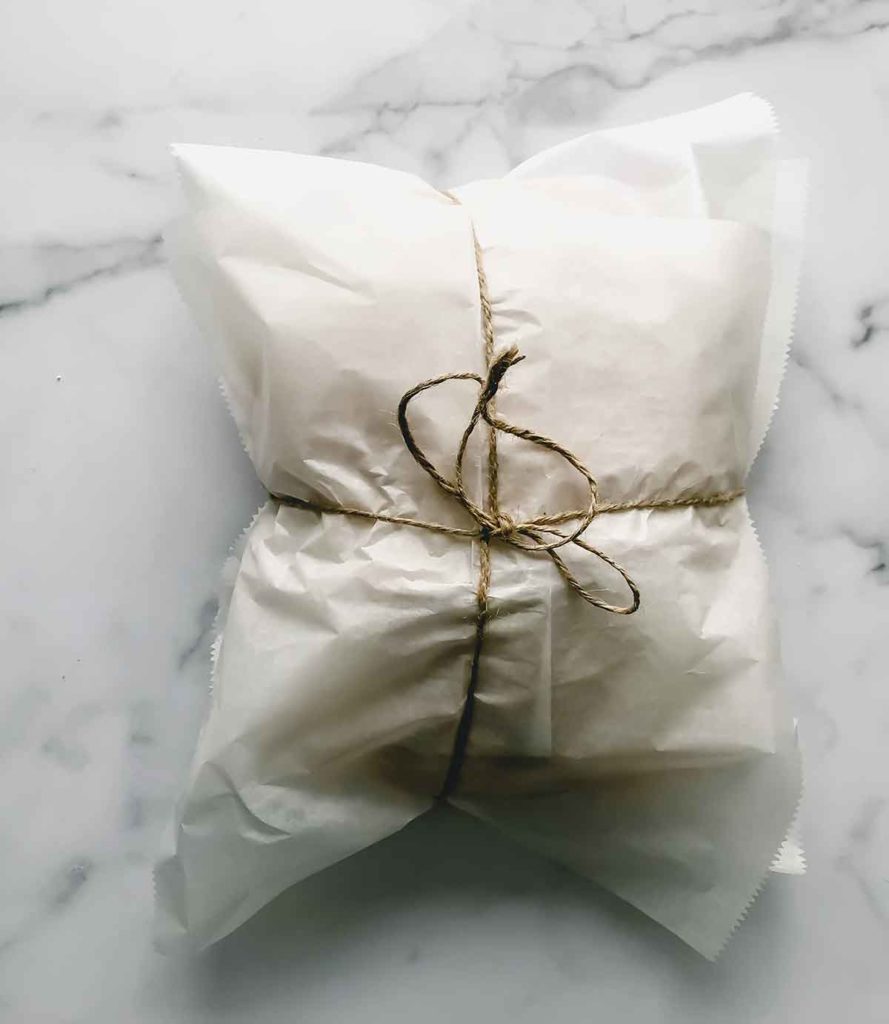 sandwich wrapped in parchment paper with kitchen twine holding it closed