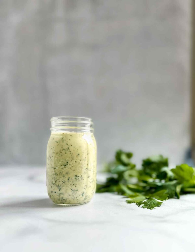 Chimichurri aioli in small glass ball jar with flat leaf parsley next to it