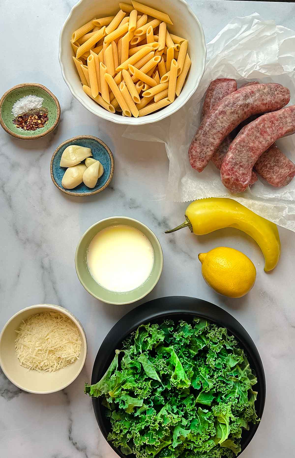 ingredients for italian sausage pasta with kale, parmesan, cream, pasta water